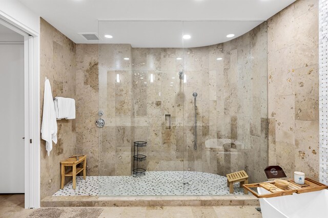 bathroom with a shower with shower door, tile patterned floors, and tile walls