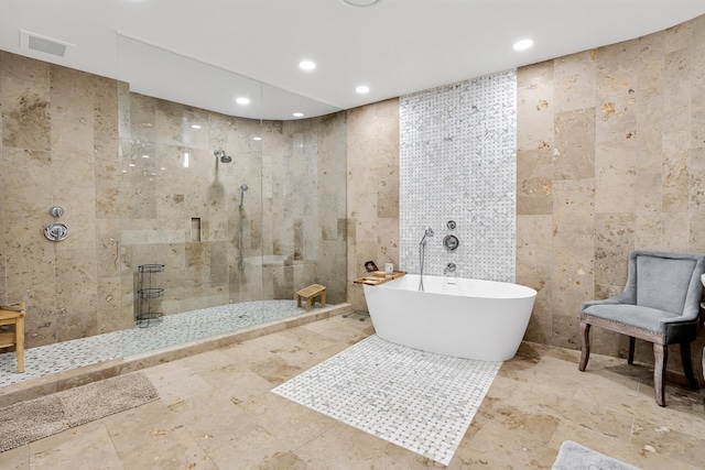 bathroom with independent shower and bath, tile patterned flooring, and tile walls