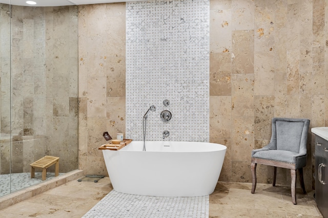 bathroom featuring independent shower and bath, vanity, tile patterned flooring, and tile walls