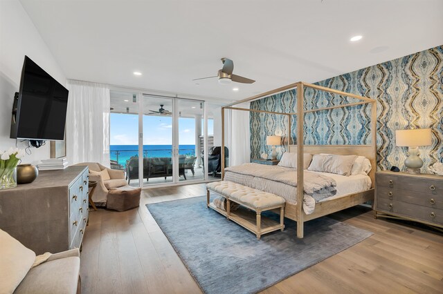 bedroom featuring a water view, access to outside, light wood-type flooring, and ceiling fan