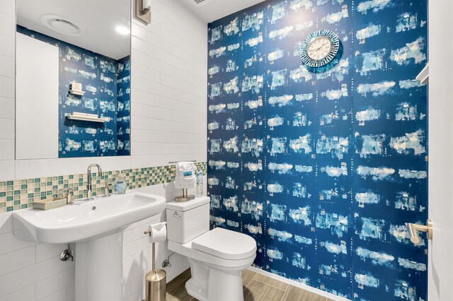 bathroom featuring tile patterned flooring, tile walls, backsplash, and toilet