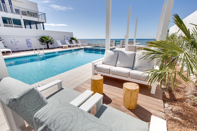 view of pool with outdoor lounge area and a water view