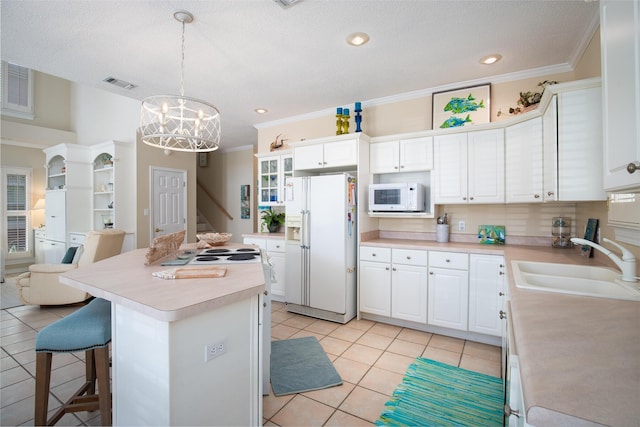 kitchen with white cabinetry, sink, a center island, decorative light fixtures, and white appliances