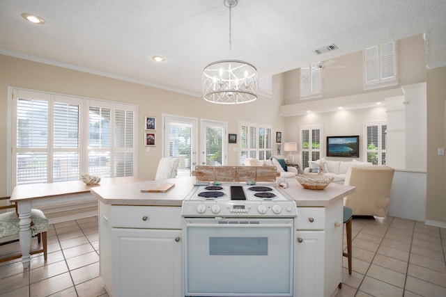 kitchen featuring white range with electric stovetop, a kitchen island, white cabinetry, and hanging light fixtures