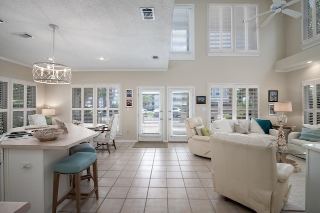 tiled living room featuring a textured ceiling, a wealth of natural light, and ceiling fan with notable chandelier