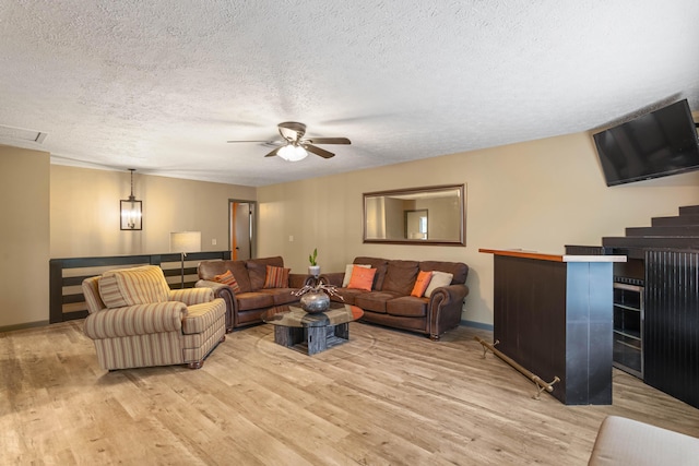 living area with baseboards, visible vents, a ceiling fan, a textured ceiling, and light wood-type flooring