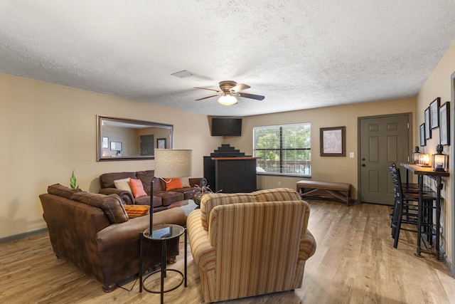 living area with a textured ceiling, light wood finished floors, and a ceiling fan