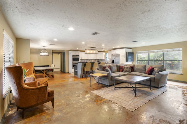 living area featuring visible vents, concrete floors, and a textured ceiling