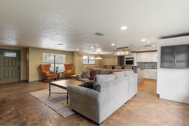 living room with concrete flooring, a textured ceiling, recessed lighting, visible vents, and baseboards