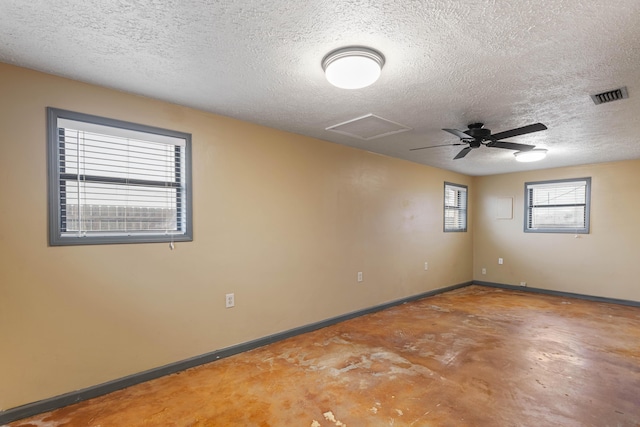 empty room featuring a textured ceiling, concrete floors, visible vents, baseboards, and attic access