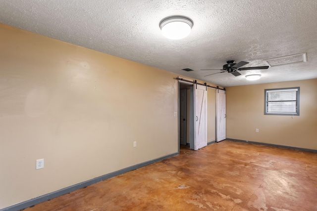 unfurnished bedroom featuring a barn door, baseboards, visible vents, a textured ceiling, and concrete flooring