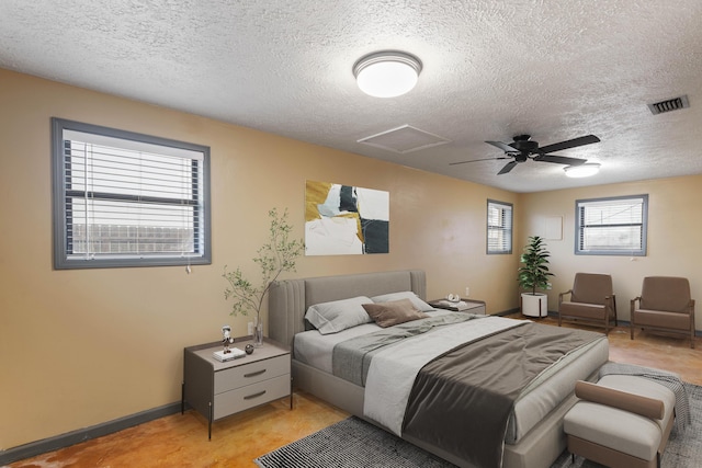 bedroom featuring a textured ceiling, a ceiling fan, baseboards, visible vents, and attic access