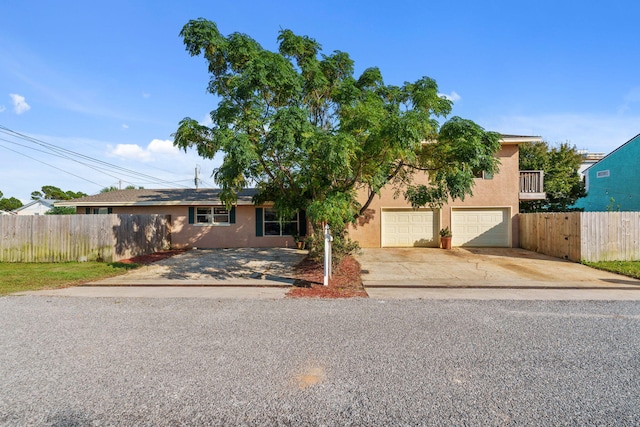 view of front facade with fence, concrete driveway, and stucco siding