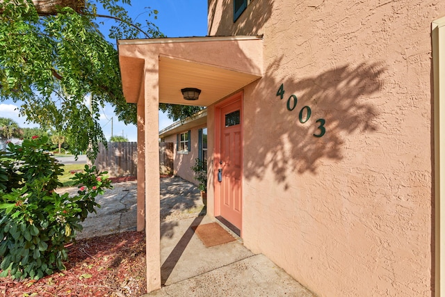 doorway to property with fence and stucco siding