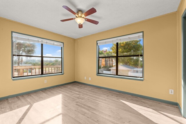 unfurnished room with a textured ceiling, light wood finished floors, a ceiling fan, and baseboards