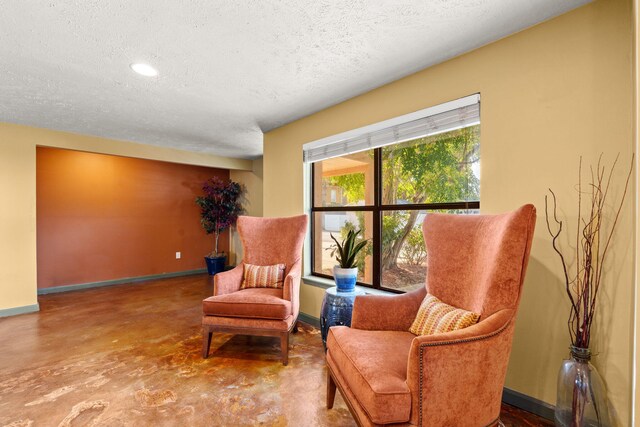 living area featuring a textured ceiling, baseboards, and concrete flooring