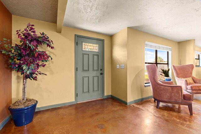 entrance foyer featuring concrete floors, a textured ceiling, and baseboards