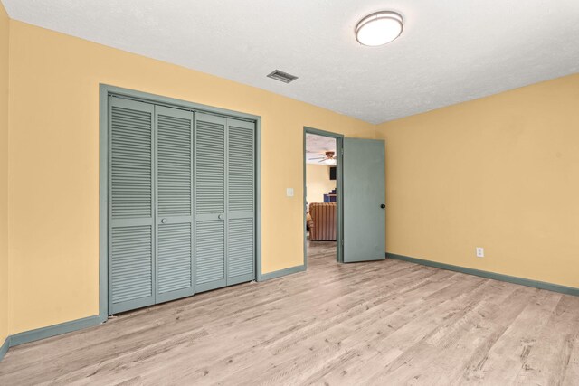 unfurnished bedroom with a closet, visible vents, baseboards, and wood finished floors