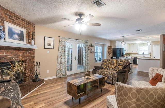 living room featuring light wood-style floors, visible vents, a wealth of natural light, and french doors