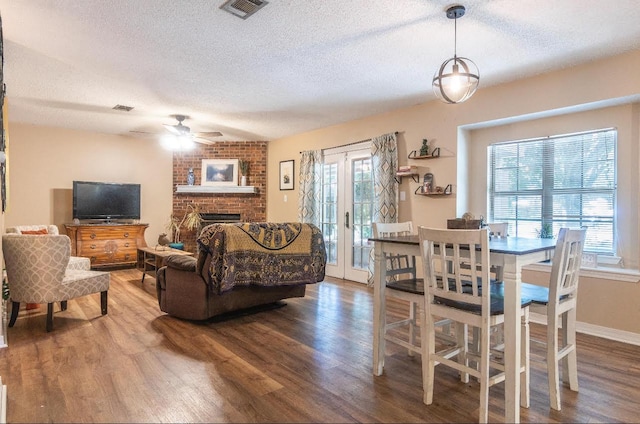 living area featuring french doors, visible vents, a fireplace, and wood finished floors