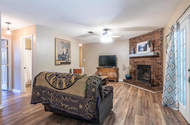 living room with a textured ceiling, a fireplace, and wood finished floors