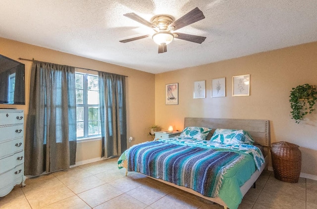 bedroom with a ceiling fan, a textured ceiling, baseboards, and light tile patterned floors