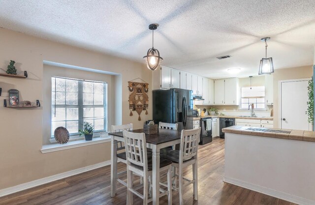 dining area with visible vents, plenty of natural light, a textured ceiling, and wood finished floors