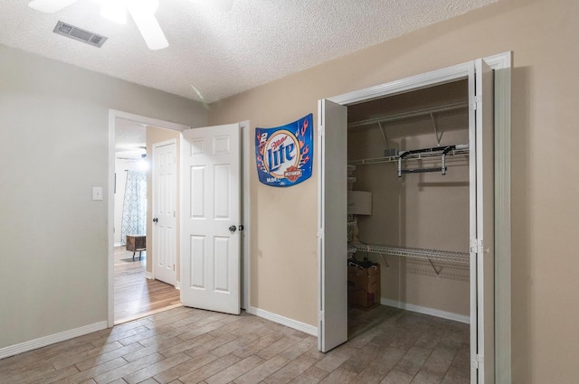 interior space with light wood finished floors, a textured ceiling, visible vents, and a closet