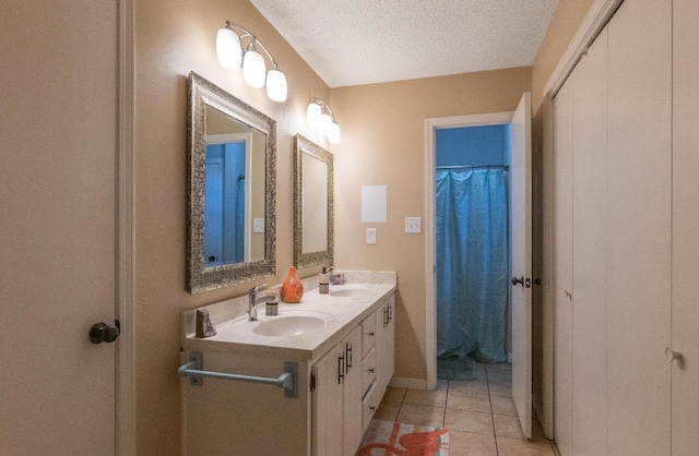 bathroom with tile patterned flooring, a sink, a textured ceiling, and double vanity