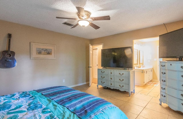 bedroom featuring a textured ceiling, ensuite bathroom, light tile patterned flooring, visible vents, and a ceiling fan