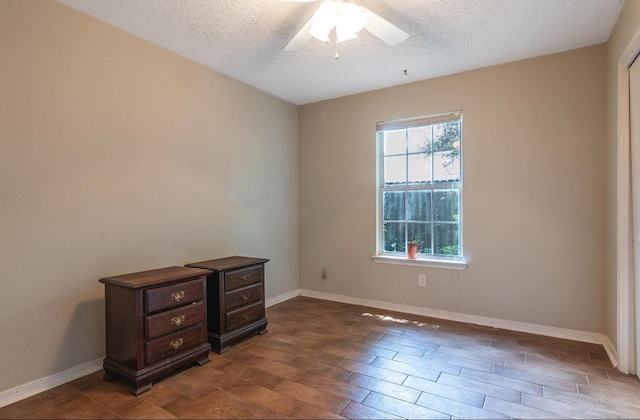 empty room with baseboards, a ceiling fan, and a textured ceiling