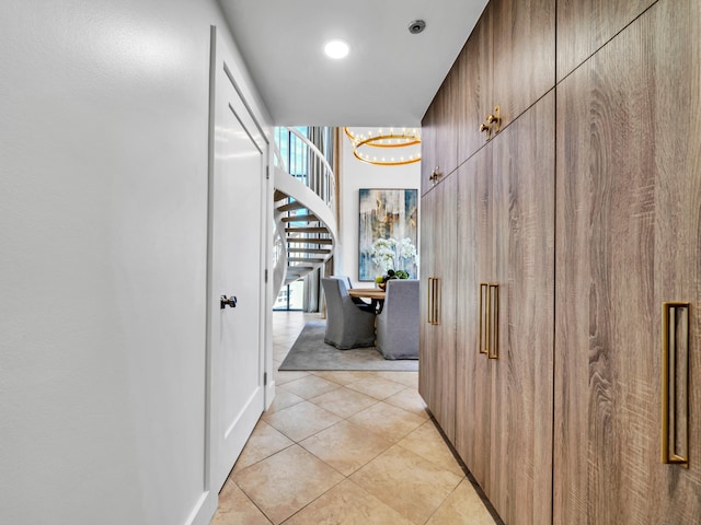 hallway with light tile patterned floors and a notable chandelier