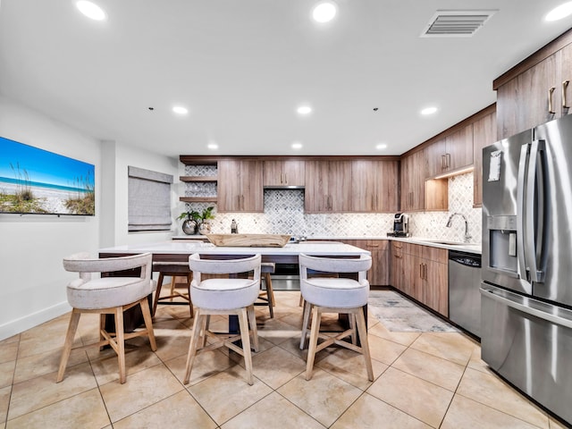 kitchen with tasteful backsplash, stainless steel appliances, light tile patterned flooring, and sink