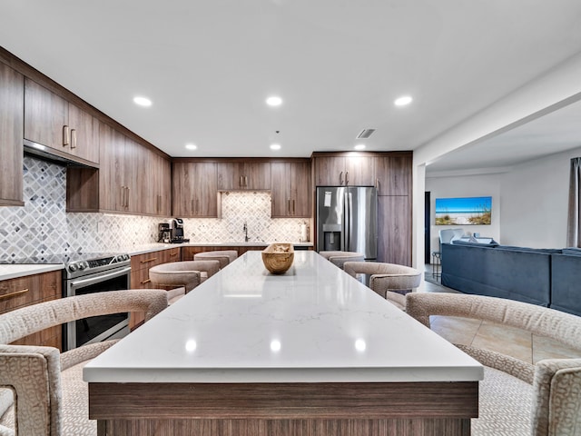 kitchen featuring tasteful backsplash, stainless steel appliances, a breakfast bar, and a kitchen island