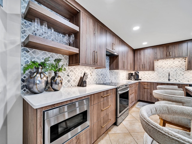 kitchen with tasteful backsplash, sink, light tile patterned floors, and appliances with stainless steel finishes