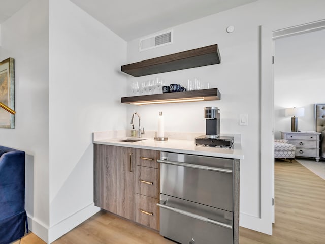 bar featuring sink and light wood-type flooring