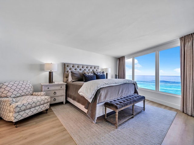 bedroom with light hardwood / wood-style floors and a water view