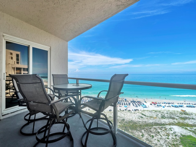 balcony with a water view and a view of the beach