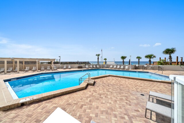 view of swimming pool with a patio and a water view