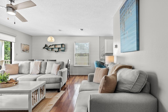 living room featuring ceiling fan, wood-type flooring, and a textured ceiling