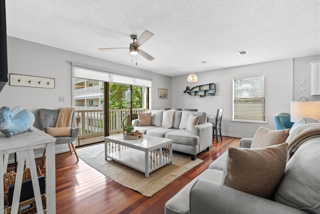 living room featuring hardwood / wood-style floors, ceiling fan, and a textured ceiling