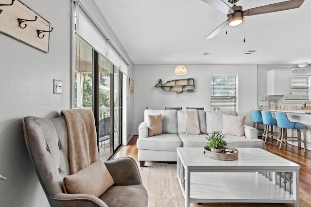 living room featuring a wealth of natural light, ceiling fan, a textured ceiling, and light wood-type flooring