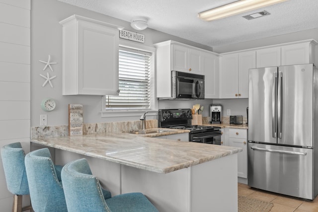 kitchen featuring black appliances, a breakfast bar, white cabinets, and kitchen peninsula