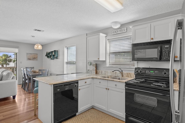 kitchen featuring black appliances, white cabinetry, kitchen peninsula, and sink