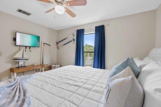 bedroom with ceiling fan and a textured ceiling