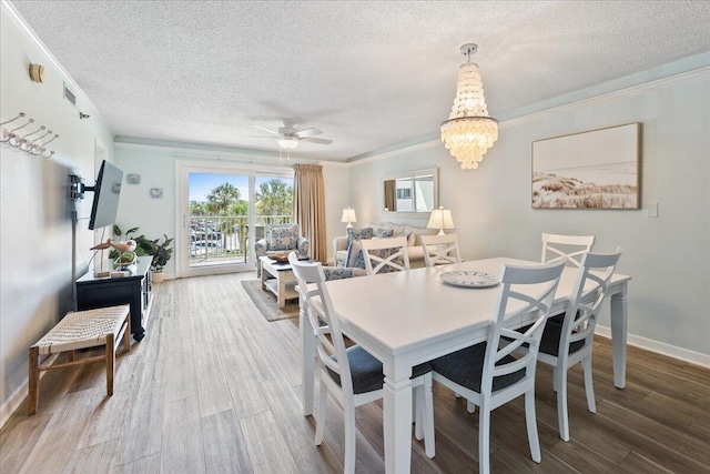 dining room with hardwood / wood-style flooring, crown molding, ceiling fan with notable chandelier, and a textured ceiling