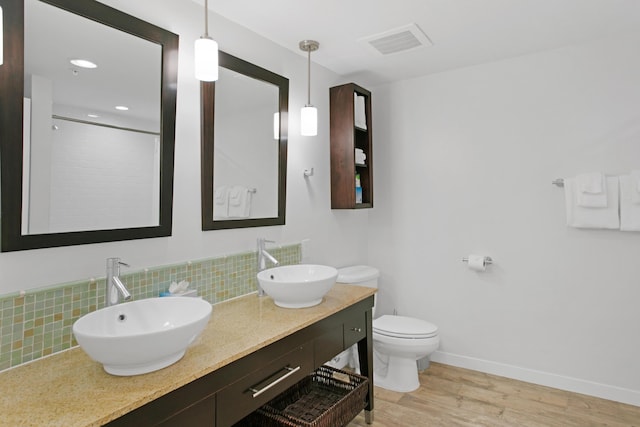 bathroom featuring decorative backsplash, walk in shower, vanity, wood-type flooring, and toilet