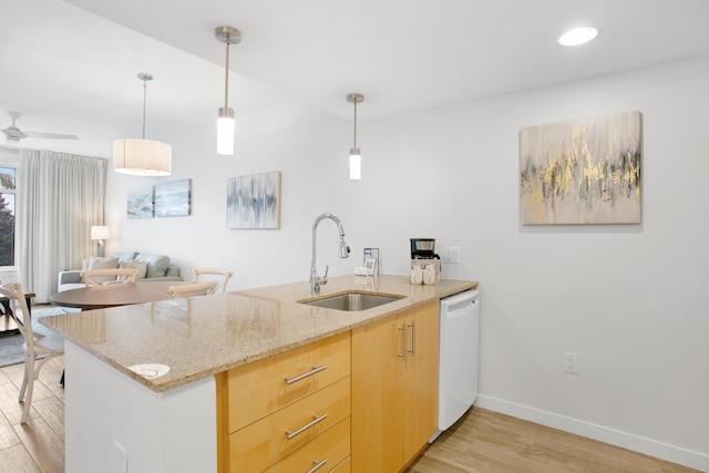 kitchen featuring dishwasher, sink, ceiling fan, light stone counters, and kitchen peninsula