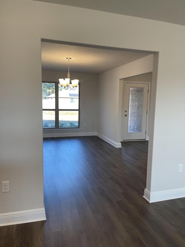 spare room with a chandelier, a textured ceiling, and dark hardwood / wood-style floors