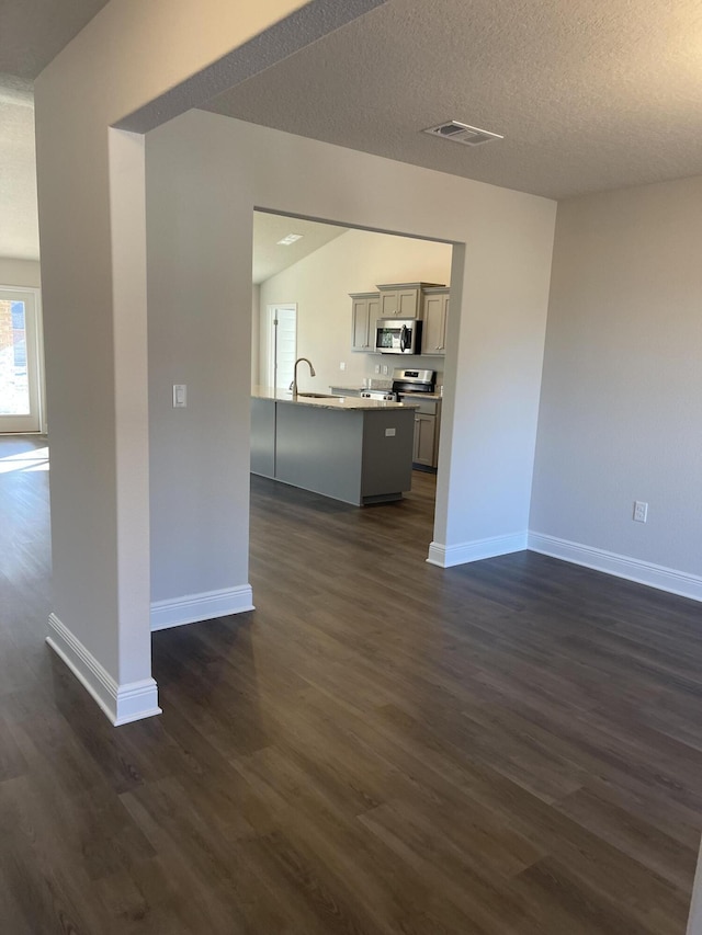 unfurnished living room with a textured ceiling, dark wood-type flooring, and sink